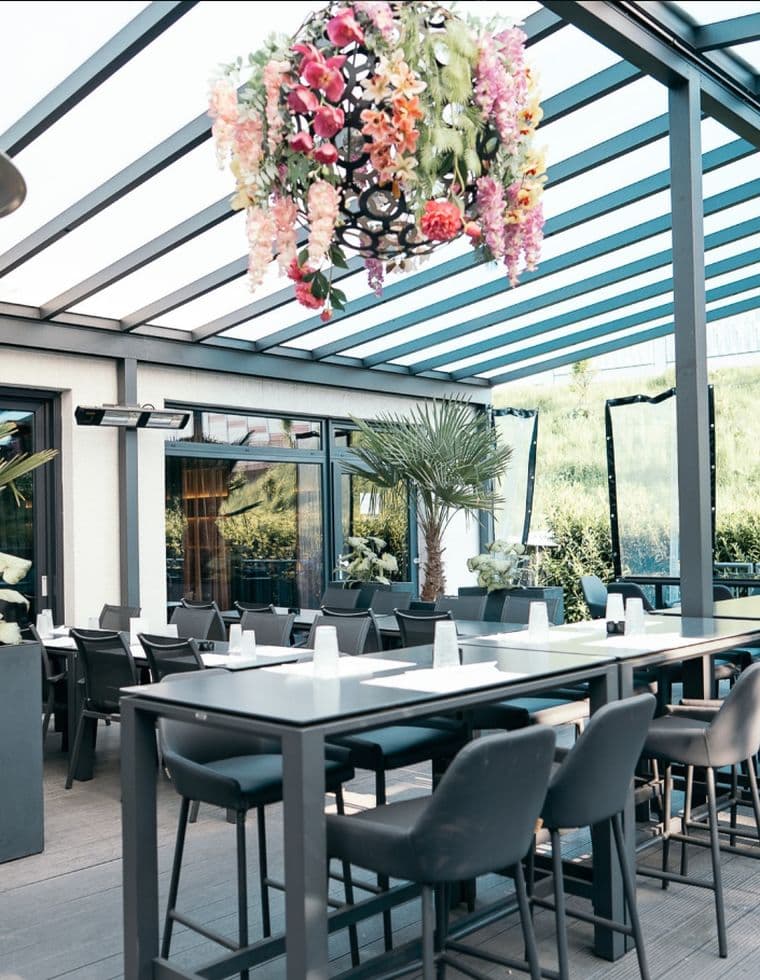 Die Veranda mit Blumenlüster unter dem Glasdach